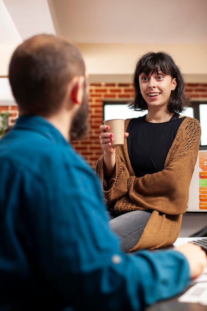 An enthusiastic business owner in a modern office discussing growth and success with a colleague.
