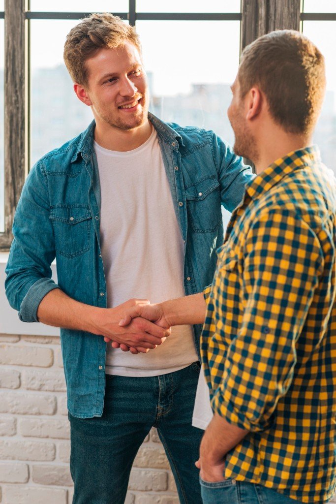 Two professional men shaking hands in a bright office, symbolizing trust and a successful business agreement.